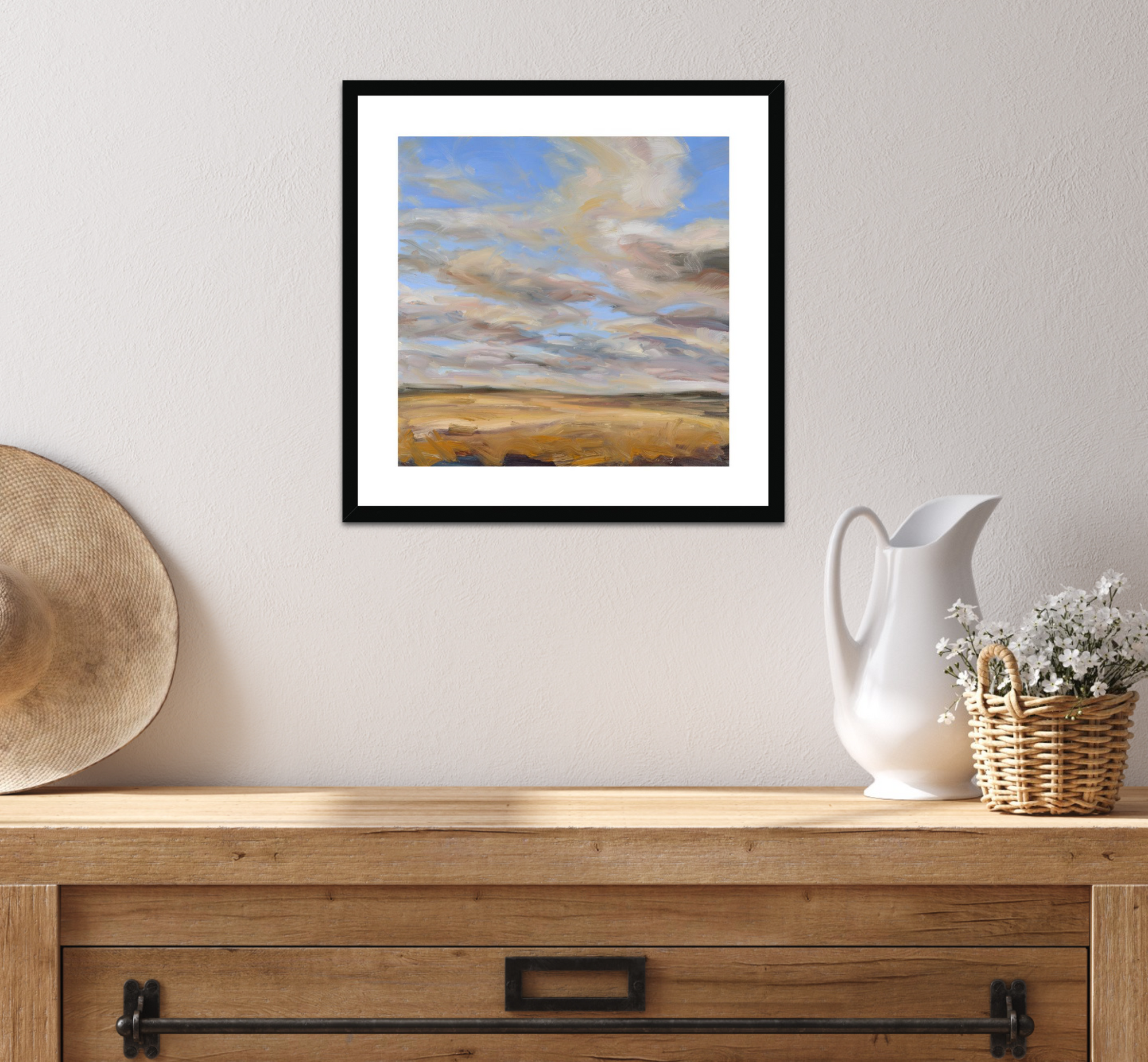 Framed landscape painting on a wall above a wooden console table with decorative items.