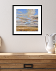 Framed landscape painting on a wall above a wooden console table with decorative items.
