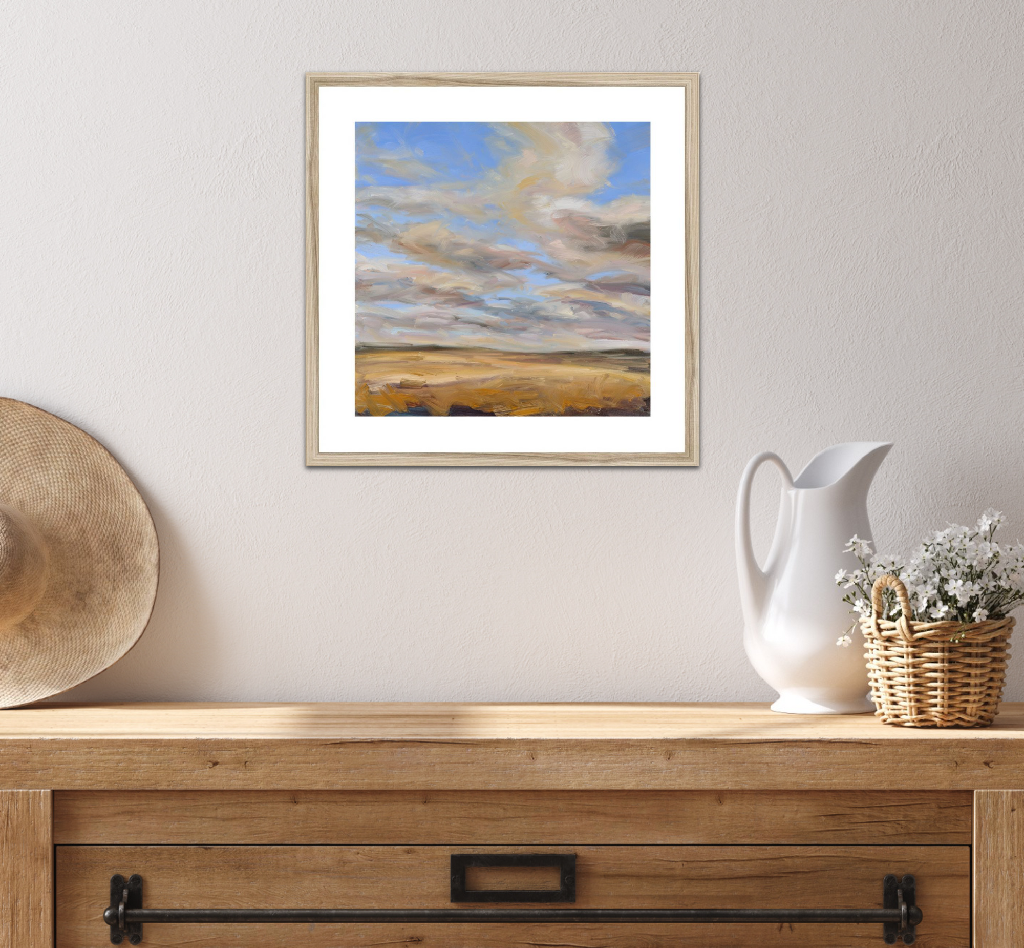 Framed landscape painting on a wall above a wooden console table with decorative items.