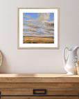Framed landscape painting on a wall above a wooden console table with decorative items.