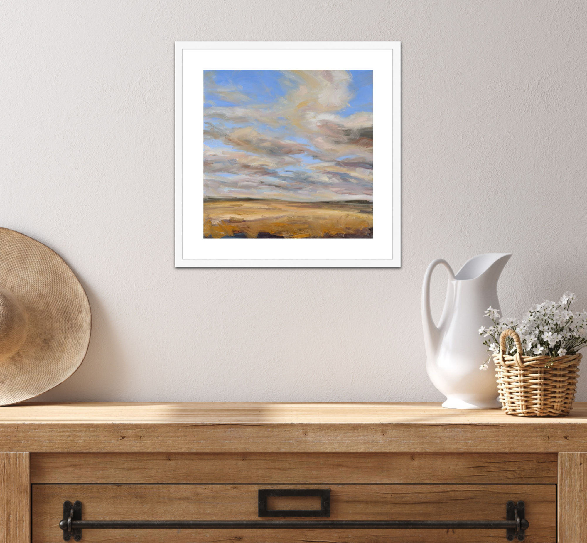 Framed landscape painting on a wall above a wooden console table with decorative items.