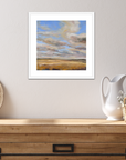 Framed landscape painting on a wall above a wooden console table with decorative items.
