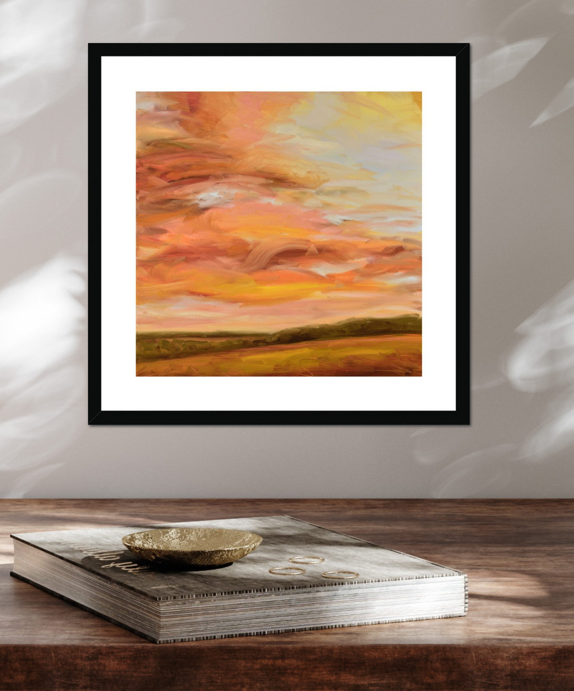 Framed abstract painting with warm colors on a wooden surface
