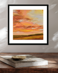 Framed abstract painting with warm colors on a wooden surface