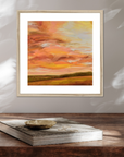 Framed abstract painting with warm colors on a wooden surface