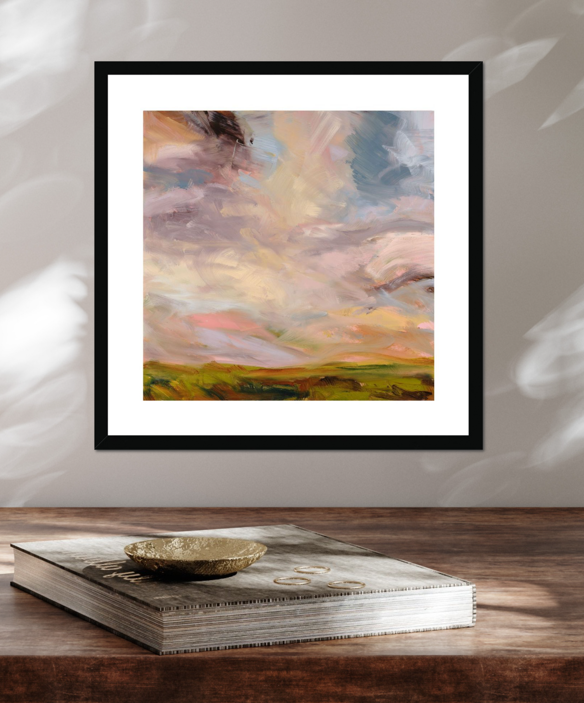 Framed abstract painting on a wooden surface with a book underneath