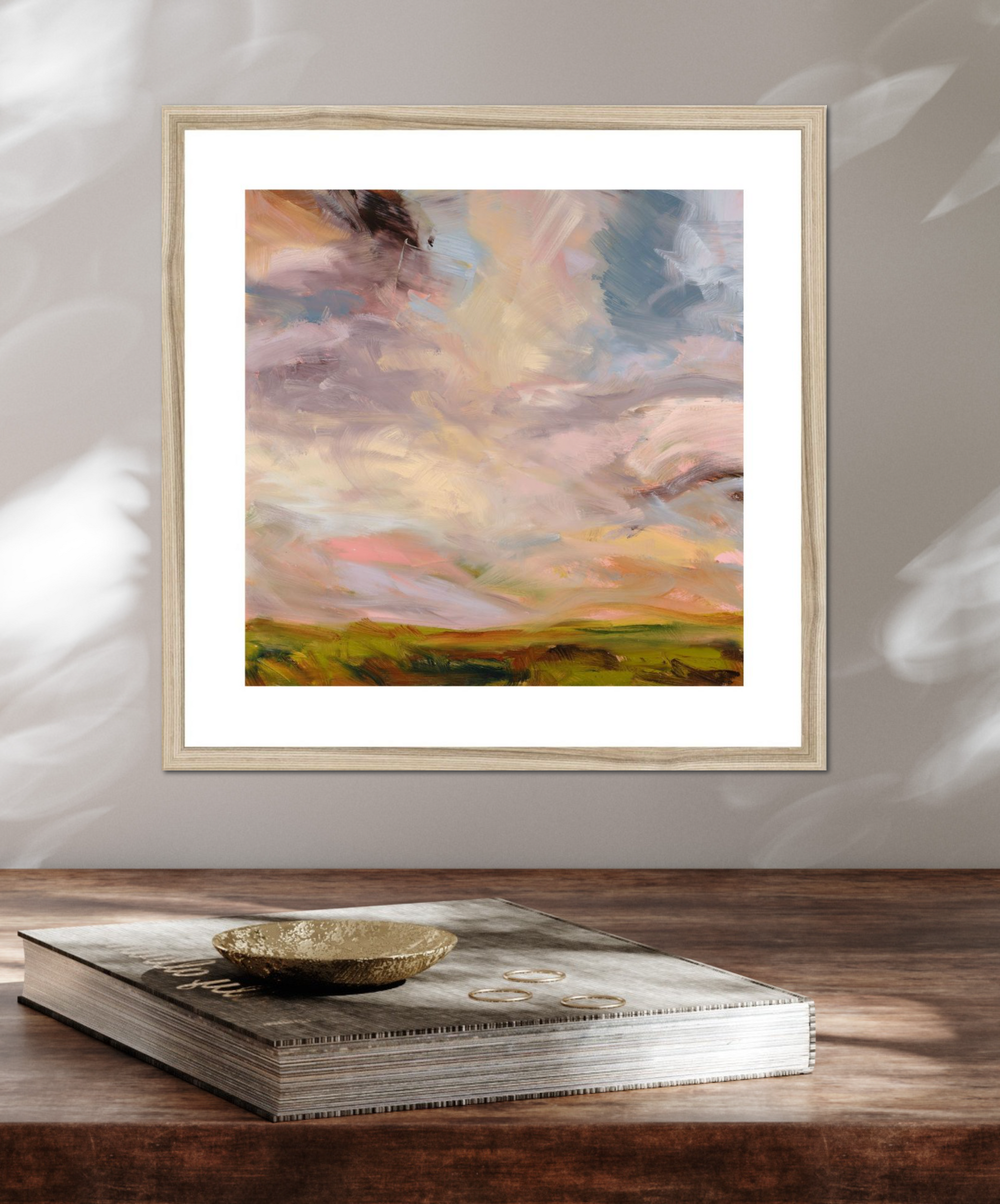 Framed abstract painting on a wooden surface with a book underneath