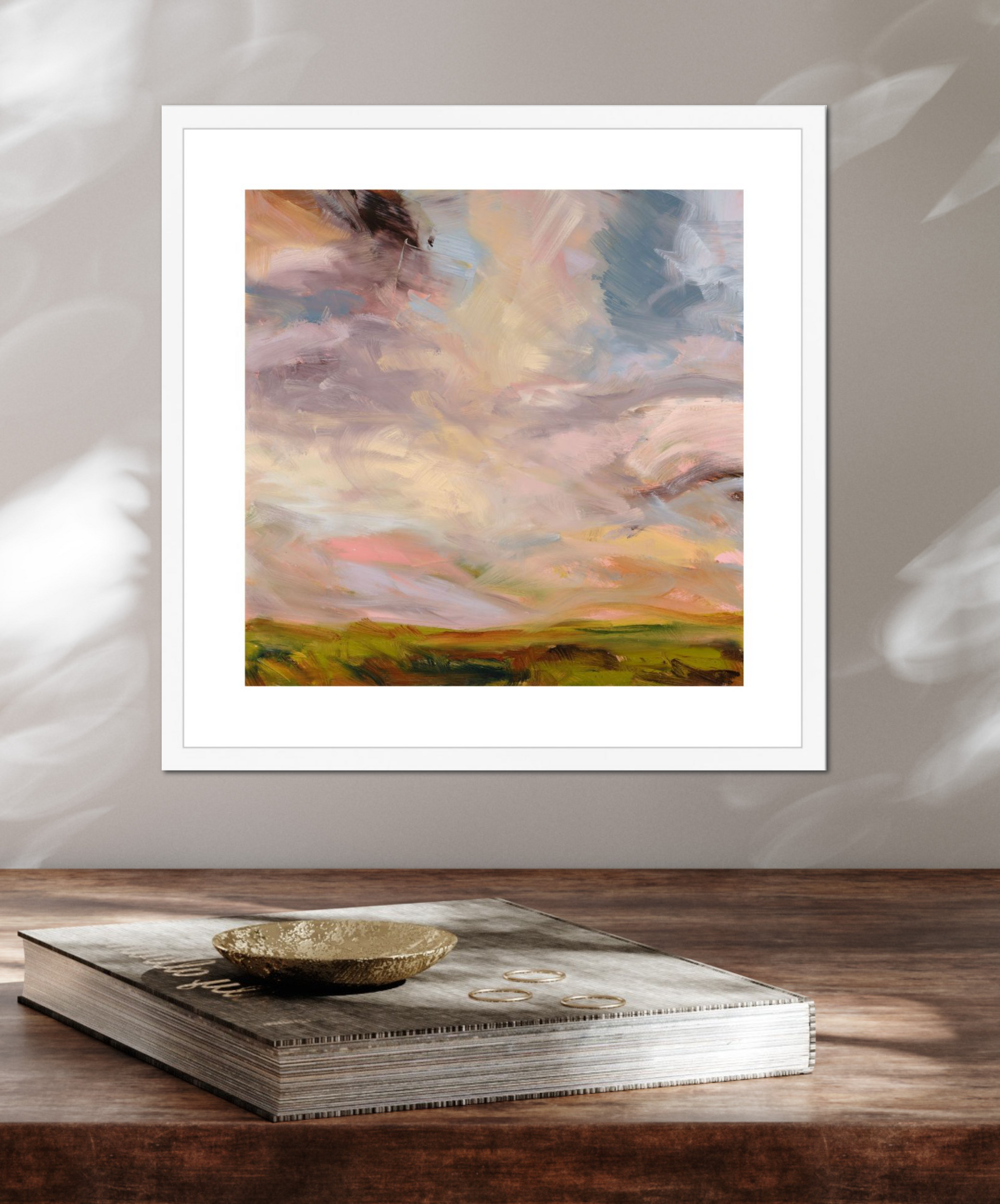 Framed abstract painting on a wooden surface with a book underneath