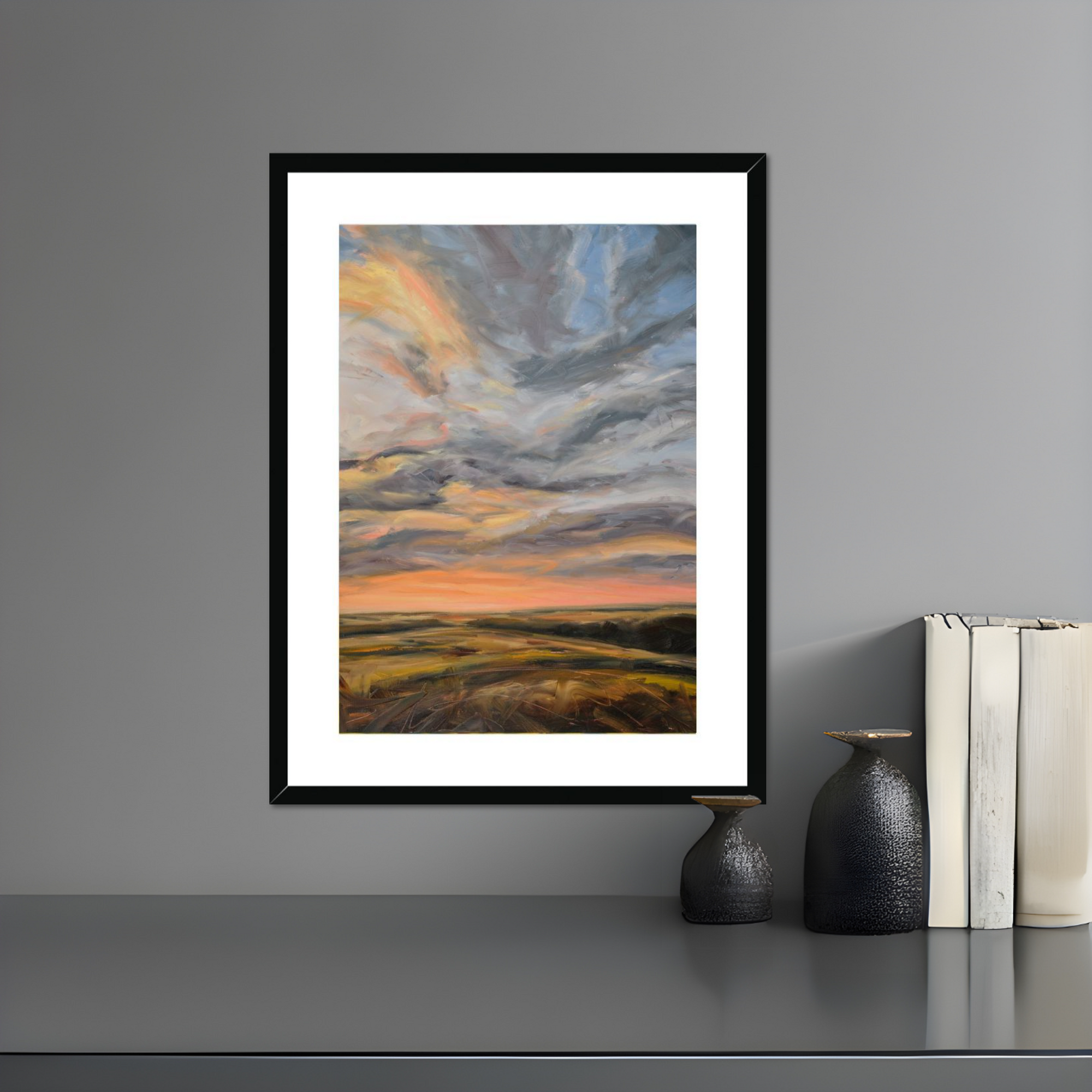 Framed artwork of a landscape with a sunset on a gray wall.