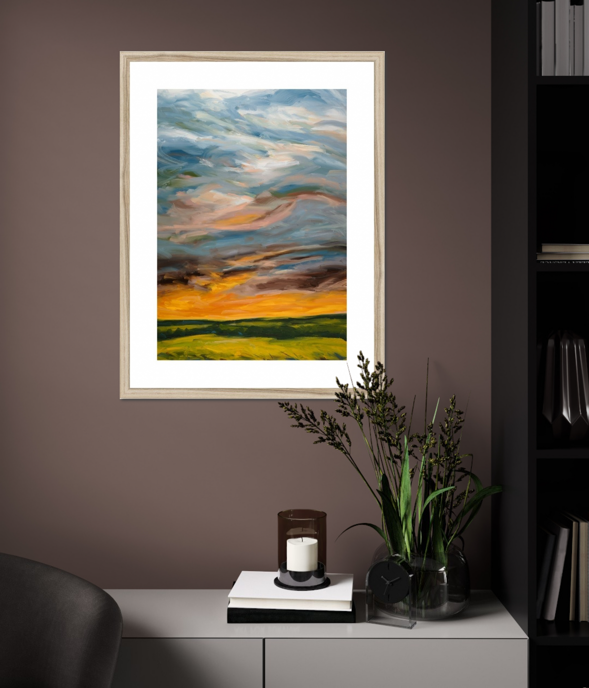 Framed abstract painting on a wall with a candle and plant on a table below.
