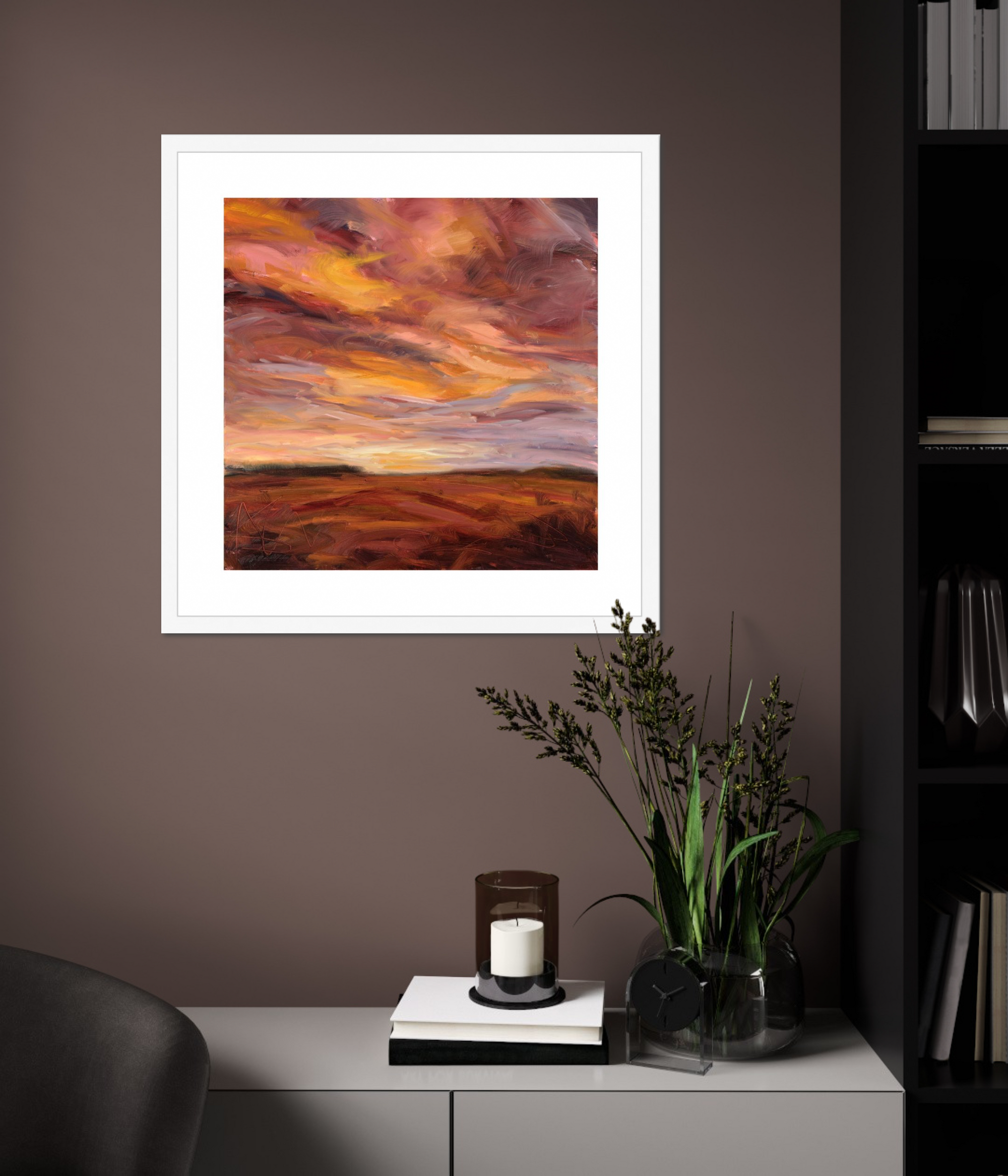 Framed artwork of a sunset over a landscape on a wall above a cabinet with decorative items.