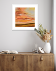 Framed abstract painting on a wall above a wooden cabinet with decorative items.
