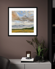 Framed landscape painting on a wall above a cabinet with decorative items.