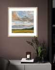 Framed landscape painting on a wall above a cabinet with decorative items.