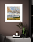 Framed landscape painting on a wall above a cabinet with decorative items.