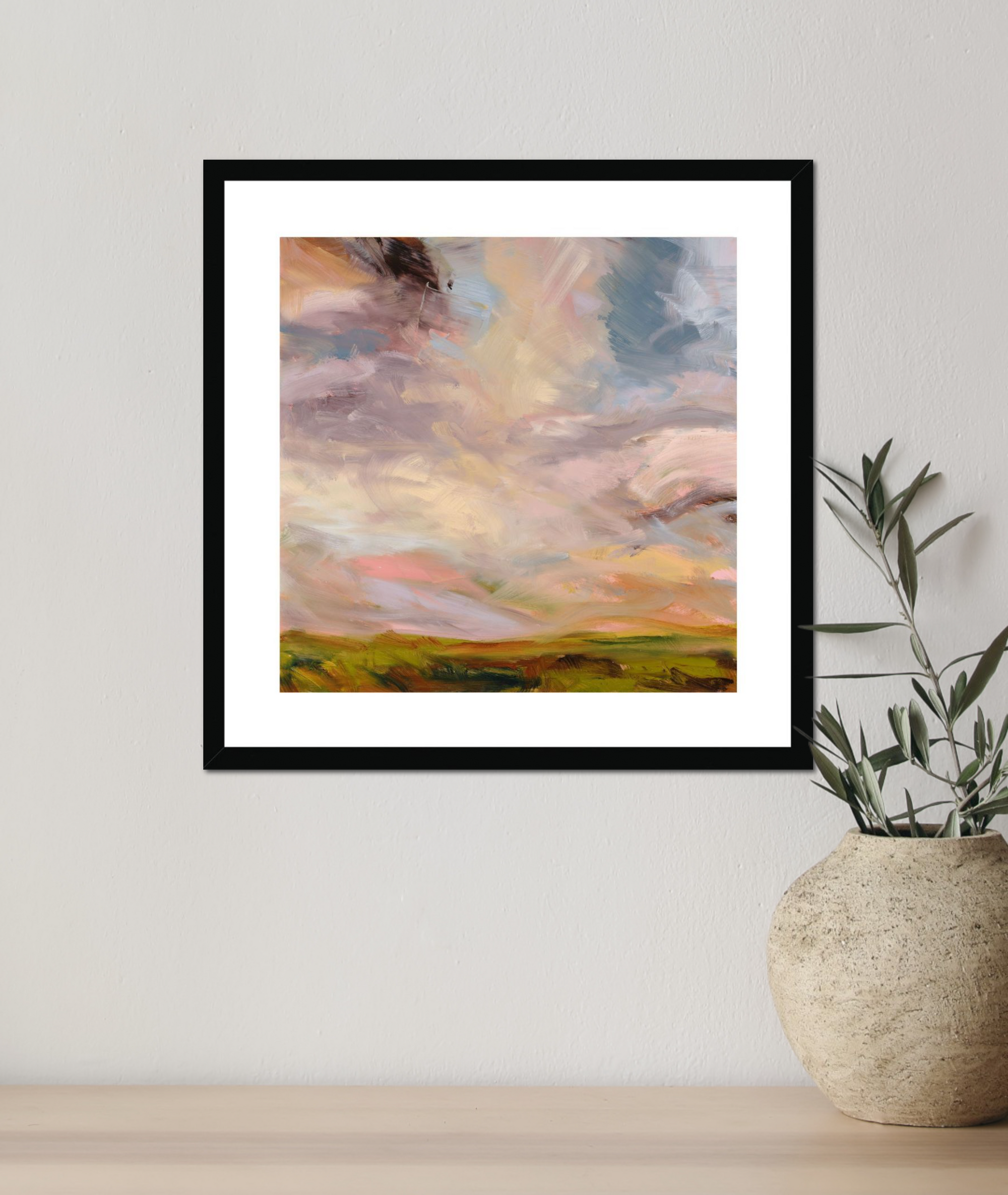 Framed abstract landscape painting on a wall next to a vase with a plant