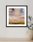 Framed abstract landscape painting on a wall next to a vase with a plant