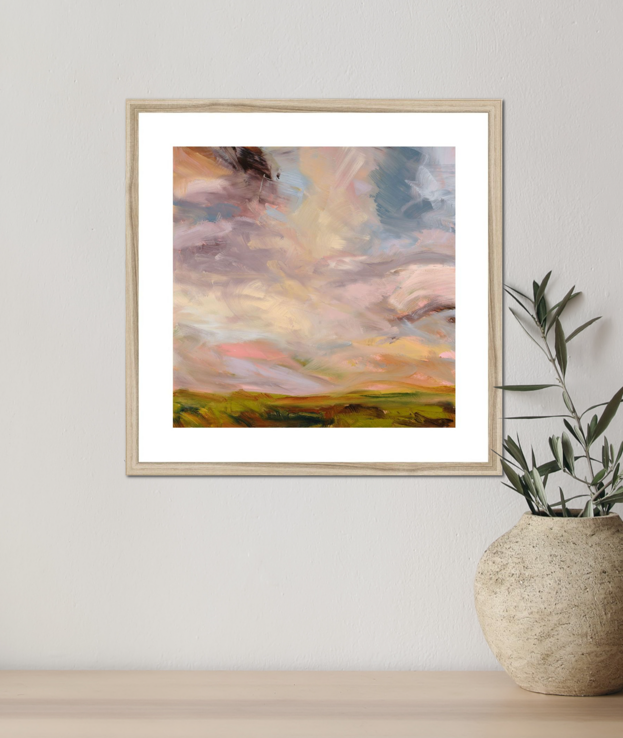 Framed abstract artwork on a wall next to a vase with plants