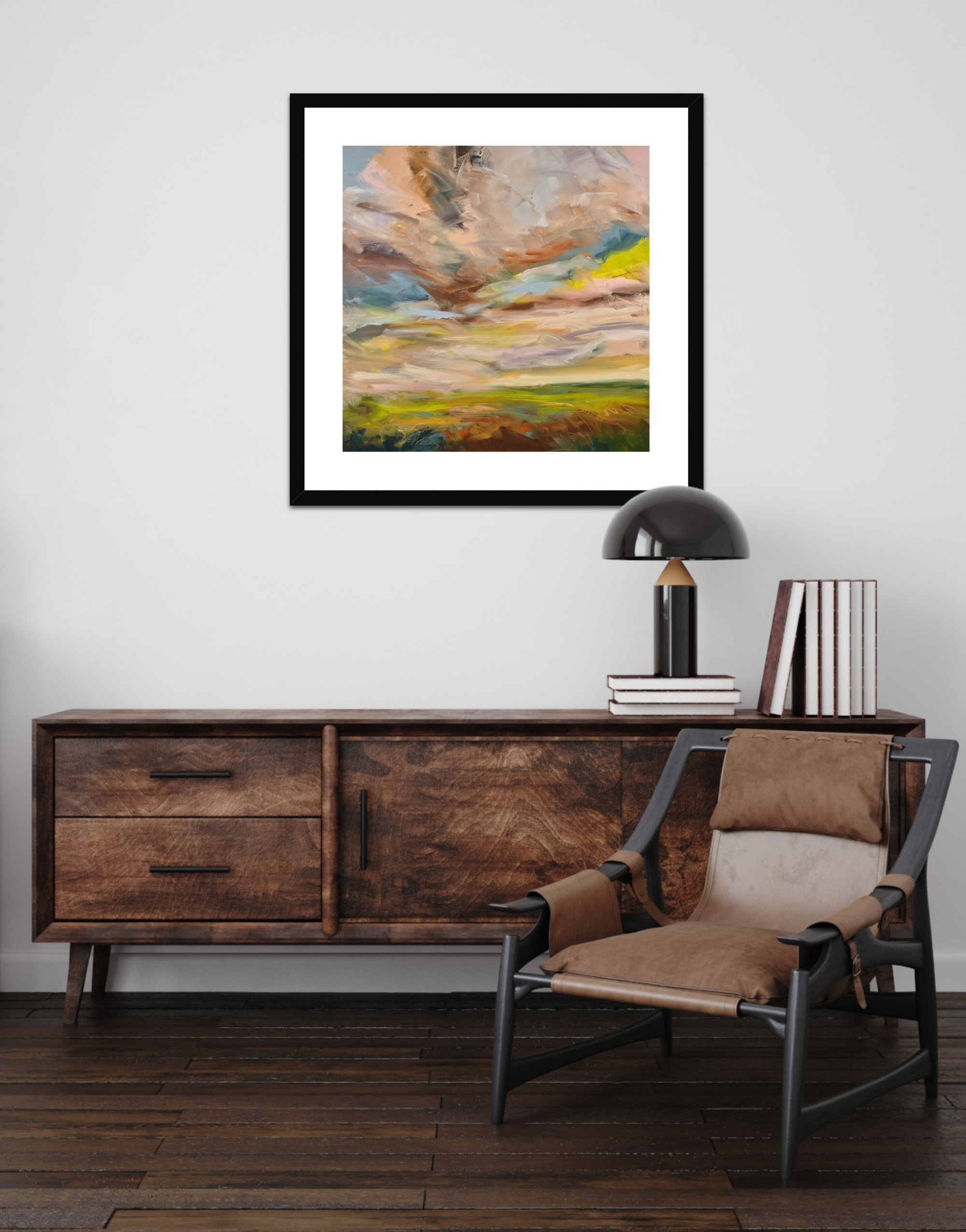 Wooden sideboard with a chair, lamp, and books against a white wall with a framed abstract painting.