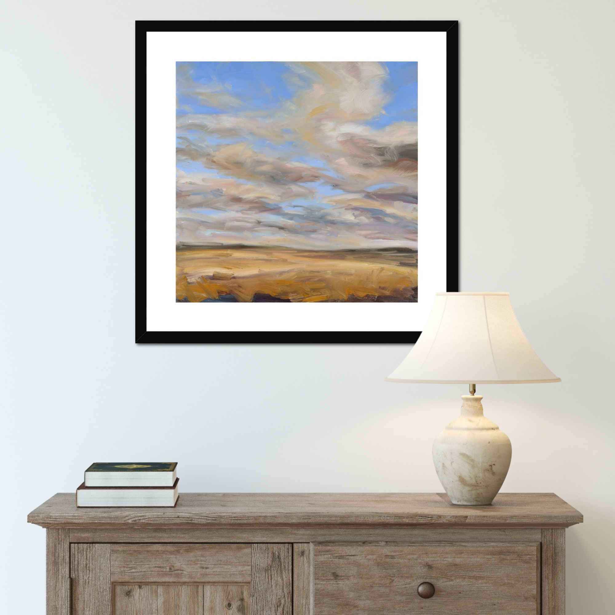 Framed abstract painting above a wooden console table with a lamp and books.