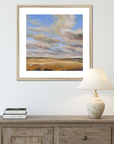 Framed landscape painting above a wooden console table with a lamp and books.