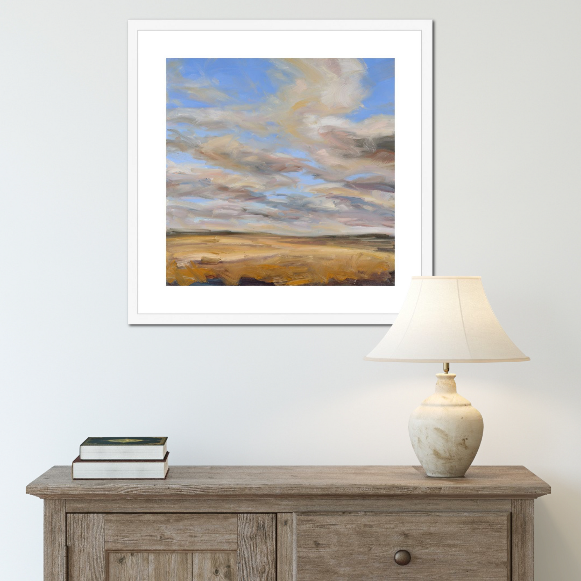 Framed abstract painting on a wall above a wooden console table with a lamp and books.