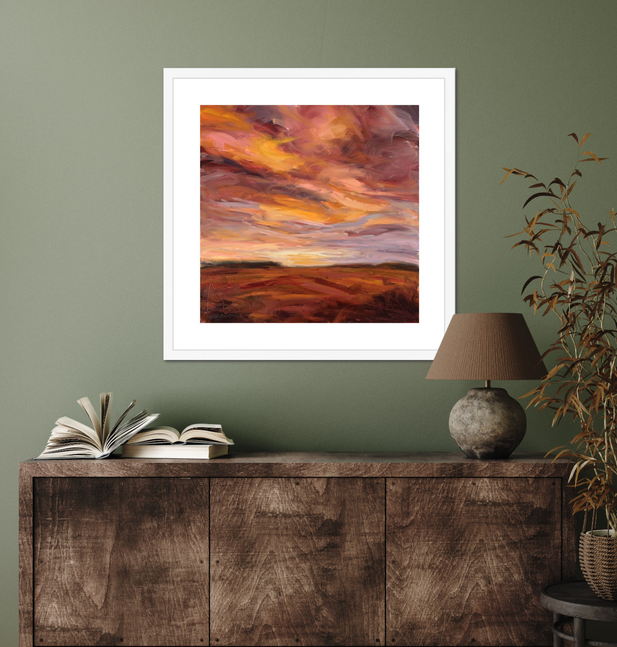 Framed abstract artwork on a wall above a wooden cabinet with books and a lamp.