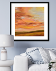 Framed abstract painting of a sunset over a field in a living room setting.