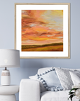 Framed abstract painting of a sunset over a field in a living room setting.