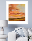 Framed abstract painting of a sunset over a field in a living room setting.