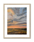 Framed painting of a sunset with swirling clouds and landscape.