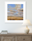Framed abstract painting on a wall above a wooden console table with a lamp and books.